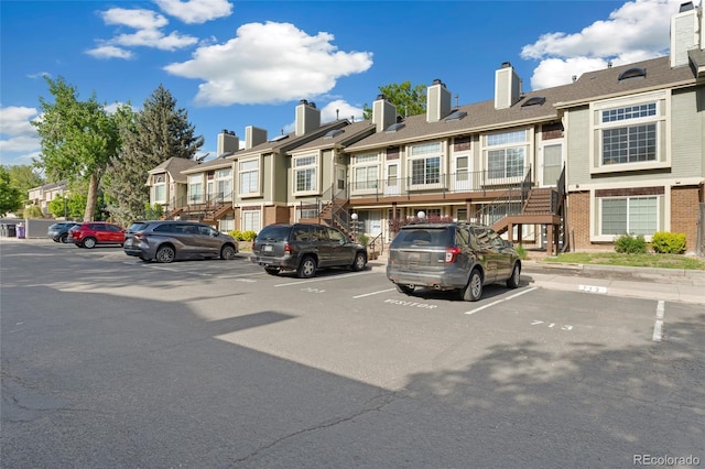 1885 S Quebec Way Unit A28, Denver, CO 80231 - view of front facade featuring a residential view, uncovered parking, stairs, and brick siding