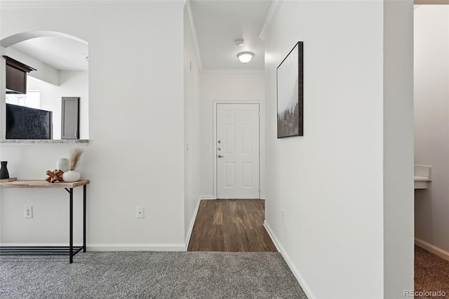 hall with arched walkways, carpet flooring, crown molding, and baseboards