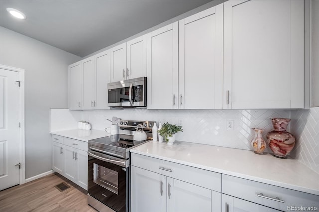 3879 N Shawnee St, Aurora, CO 80019 - kitchen with stainless steel appliances, light countertops, light wood-style flooring, and backsplash