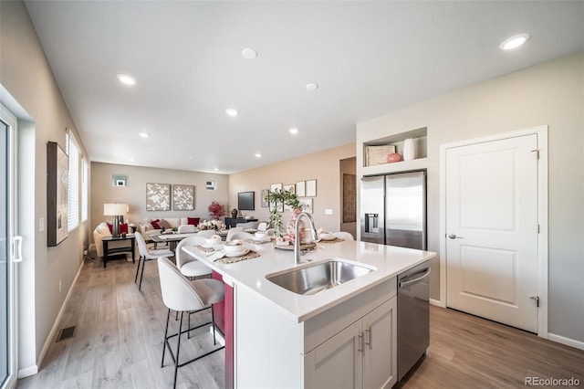 3879 N Shawnee St, Aurora, CO 80019 - kitchen featuring a sink, stainless steel appliances, light wood-type flooring, light countertops, and a kitchen island with sink