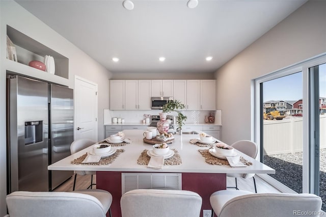 3879 N Shawnee St, Aurora, CO 80019 - kitchen featuring appliances with stainless steel finishes, a sink, a kitchen bar, white cabinets, and recessed lighting