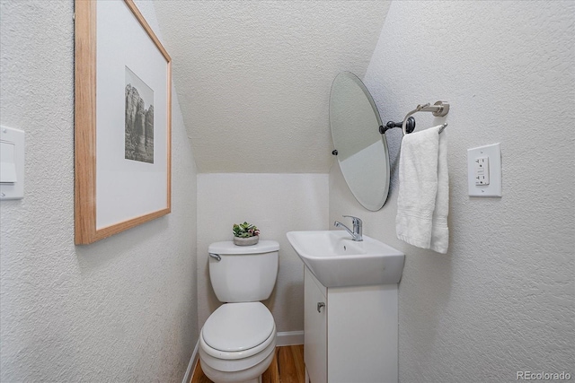 bathroom featuring a textured ceiling, vanity, toilet, and lofted ceiling