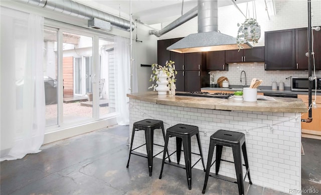 kitchen featuring island range hood, concrete floors, decorative backsplash, and stainless steel appliances