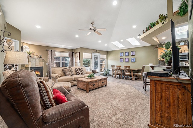 living room featuring a fireplace, light wood-type flooring, ceiling fan, and lofted ceiling