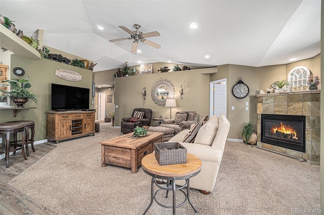 living room featuring a tile fireplace, hardwood / wood-style floors, vaulted ceiling, and ceiling fan