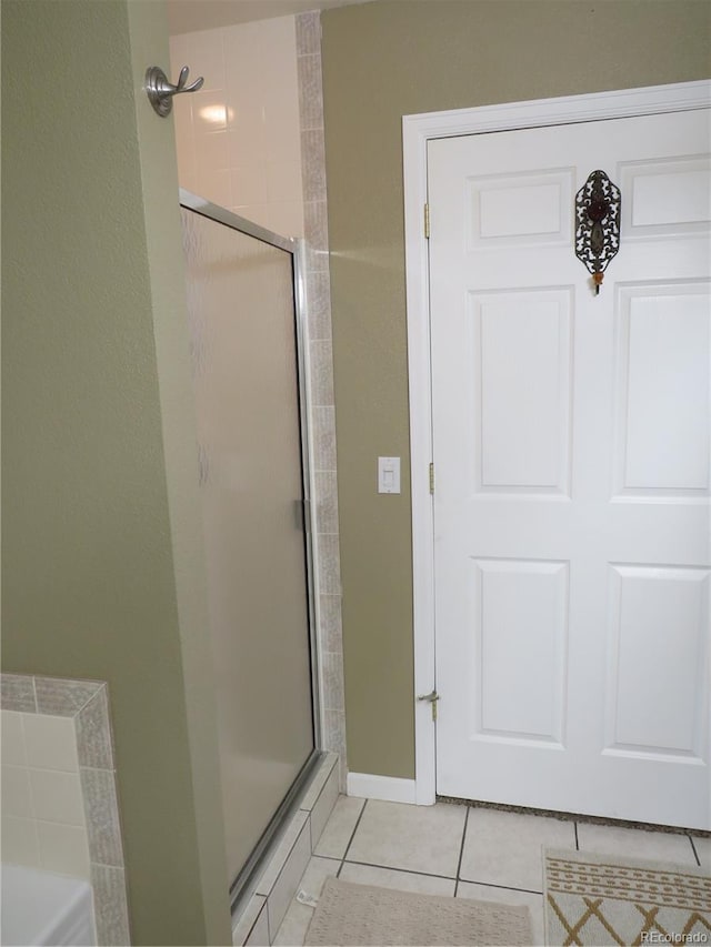 bathroom with tile patterned floors and a shower with door