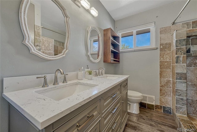 7541 Julian St, Westminster, CO 80030 - bathroom featuring toilet, tiled shower, wood finished floors, and double vanity