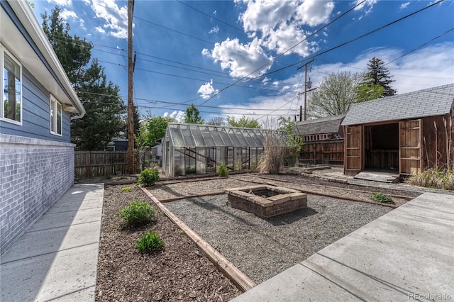 7541 Julian St, Westminster, CO 80030 - fenced backyard featuring a greenhouse, an outdoor structure, and an outdoor fire pit