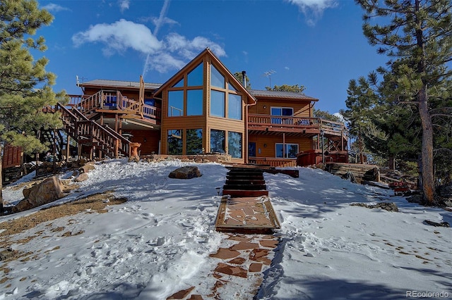 snow covered back of property with a deck