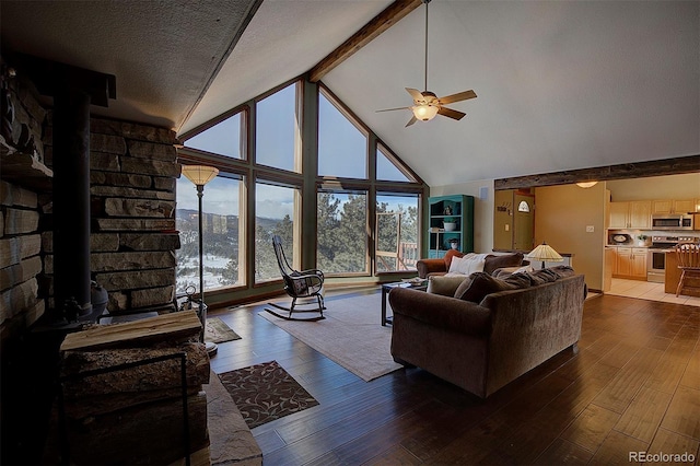 living room featuring high vaulted ceiling, a wood stove, hardwood / wood-style floors, and ceiling fan