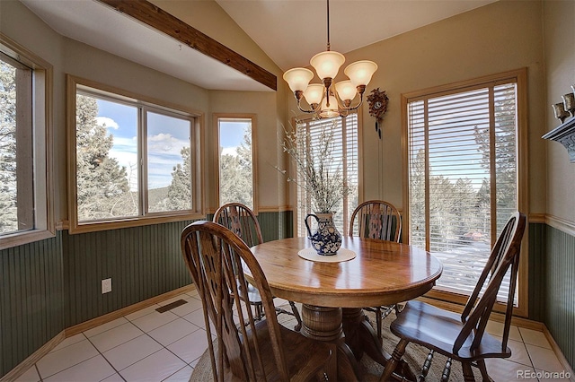 tiled dining space featuring lofted ceiling, a wealth of natural light, and an inviting chandelier