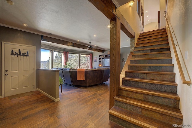 stairs featuring wood-type flooring, ceiling fan, and a textured ceiling