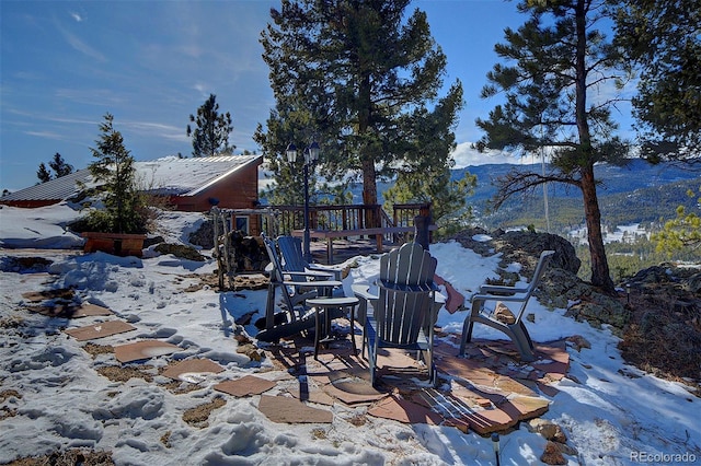 snow covered patio featuring a playground and a mountain view