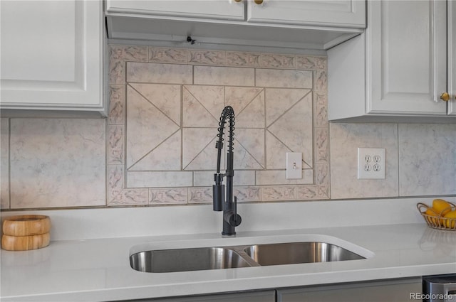 kitchen featuring white cabinets, tasteful backsplash, light countertops, and a sink