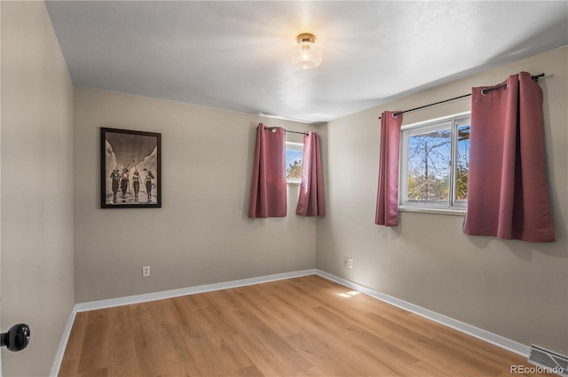 empty room featuring light wood-style floors, baseboards, and plenty of natural light