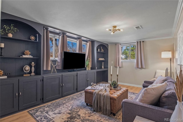 living room featuring visible vents, built in shelves, wood finished floors, and baseboards