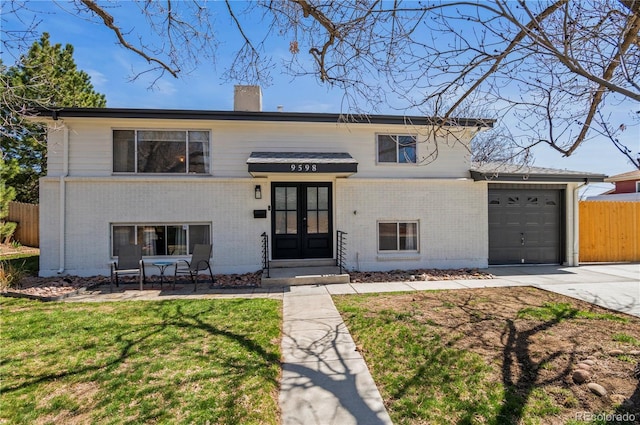 view of front of property with fence, a front lawn, brick siding, french doors, and driveway