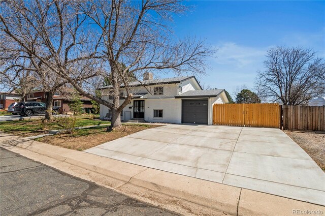 traditional home featuring a garage, fence, a gate, a chimney, and concrete driveway
