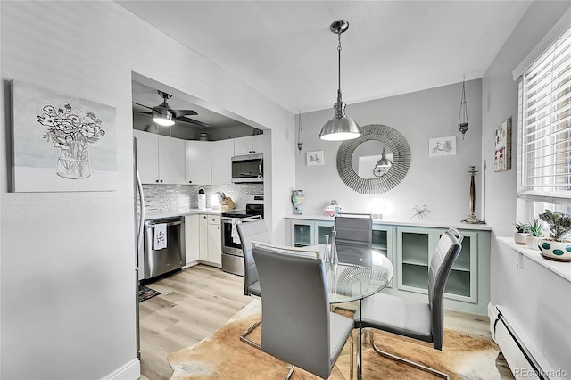 dining area featuring ceiling fan, a baseboard radiator, and light wood-type flooring