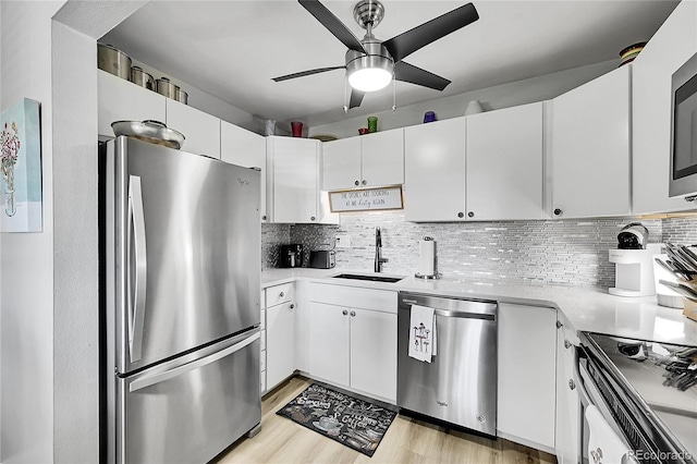 kitchen with backsplash, sink, white cabinetry, appliances with stainless steel finishes, and light hardwood / wood-style floors