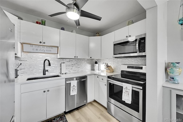 kitchen featuring white cabinets, backsplash, light wood-type flooring, sink, and stainless steel appliances