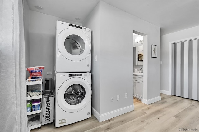 washroom featuring stacked washer / drying machine, sink, and light wood-type flooring