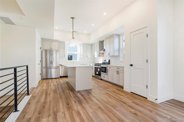 kitchen with decorative light fixtures, a center island, stainless steel appliances, and light hardwood / wood-style floors