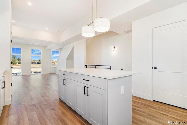 kitchen with pendant lighting, a center island, white cabinetry, and light hardwood / wood-style flooring