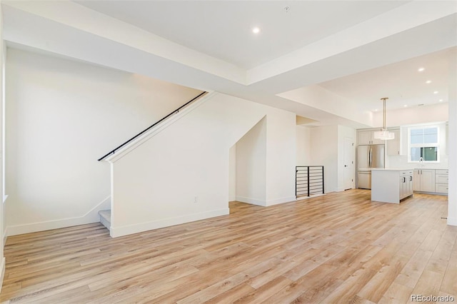 unfurnished living room with sink and light hardwood / wood-style flooring