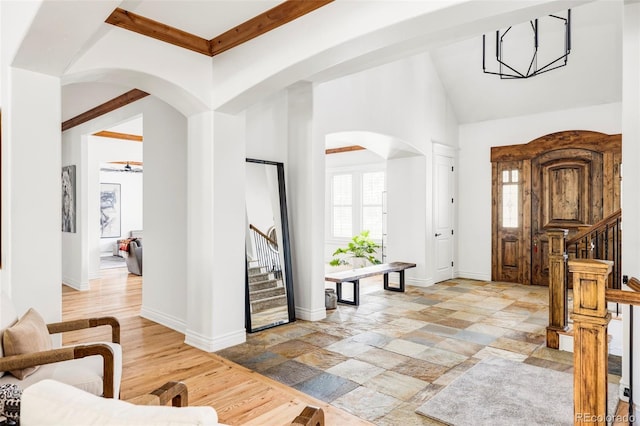 foyer entrance featuring high vaulted ceiling, beam ceiling, ceiling fan with notable chandelier, and light hardwood / wood-style flooring