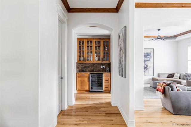 bar with wine cooler, ceiling fan, light hardwood / wood-style flooring, crown molding, and decorative backsplash