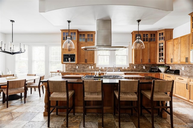 kitchen with island exhaust hood, a healthy amount of sunlight, backsplash, and decorative light fixtures