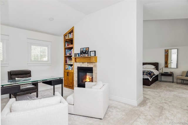 carpeted home office with built in shelves, a fireplace, and lofted ceiling