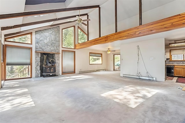 3909 County Road 72, Bailey, CO 80421 - unfurnished living room featuring baseboard heating, ceiling fan, a wood stove, healthy amount of natural light, and beam ceiling