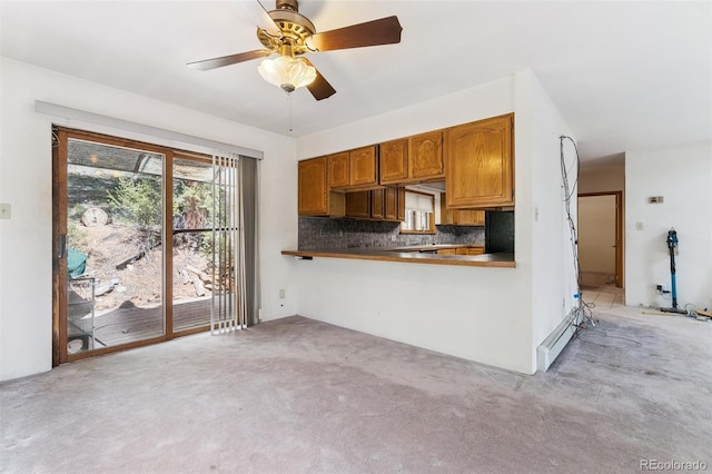 3909 County Road 72, Bailey, CO 80421 - kitchen with light colored carpet, decorative backsplash, a ceiling fan, brown cabinetry, and dark countertops