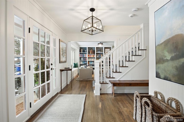 entrance foyer featuring dark wood-type flooring, ornamental molding, and a chandelier