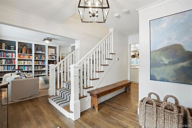 staircase featuring a notable chandelier, hardwood / wood-style flooring, and ornamental molding