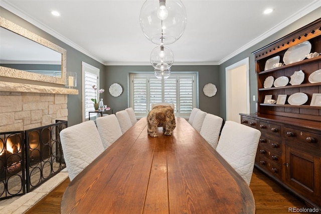 dining area with dark wood-type flooring, ornamental molding, and a fireplace