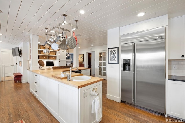 kitchen with hardwood / wood-style floors, wooden counters, wood ceiling, white cabinetry, and stainless steel built in fridge