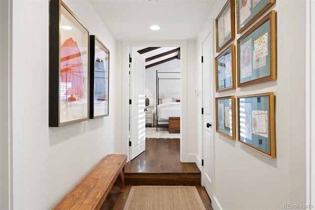 corridor with wood-type flooring and lofted ceiling with beams