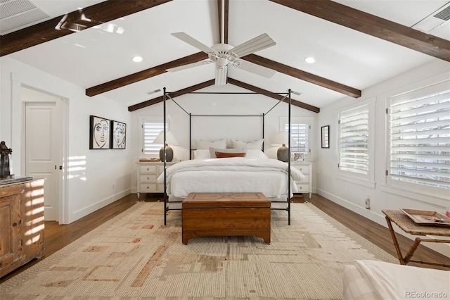 bedroom featuring ceiling fan, light hardwood / wood-style floors, multiple windows, and vaulted ceiling with beams