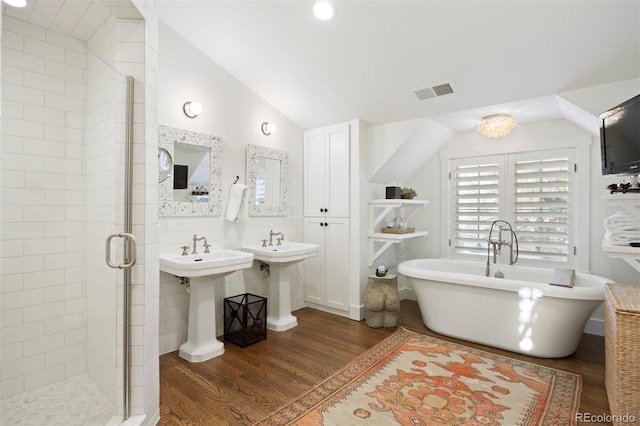 bathroom with dual sinks, hardwood / wood-style floors, tile walls, and lofted ceiling