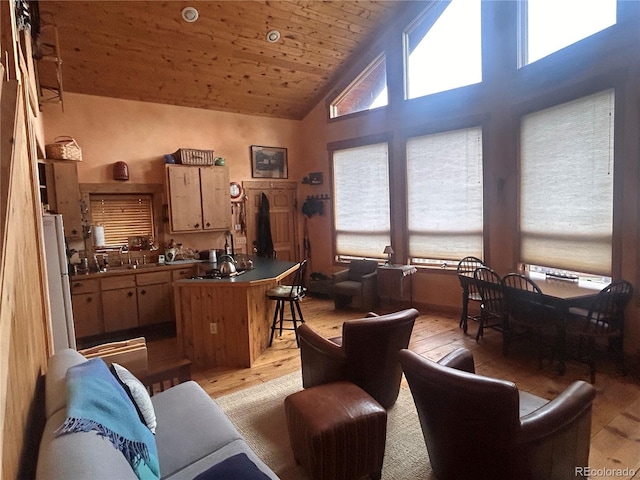 kitchen featuring light wood-style floors, high vaulted ceiling, wooden ceiling, a breakfast bar, and dark countertops
