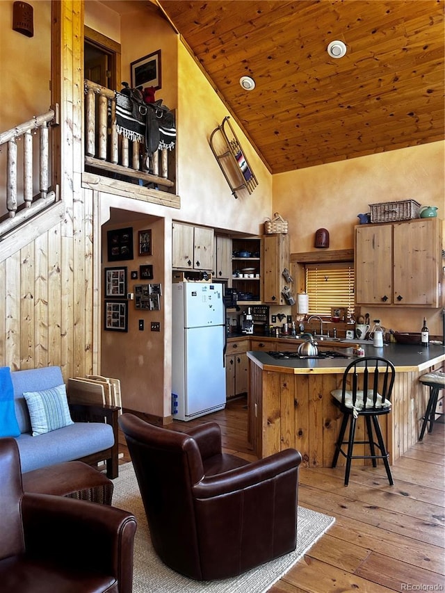 kitchen with freestanding refrigerator, high vaulted ceiling, wood ceiling, light wood finished floors, and dark countertops