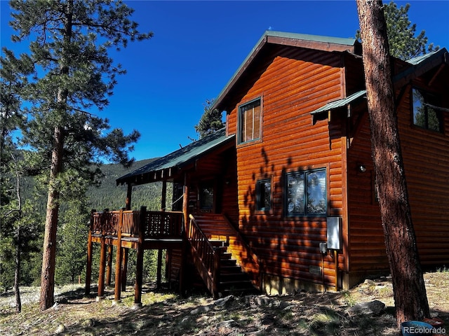 back of property with a deck, faux log siding, and stairway