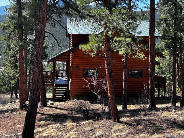 view of side of property with log veneer siding, a wooden deck, a metal roof, and stairway