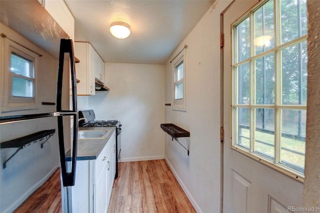 1707 W 39th Ave, Denver, CO 80211 - kitchen with black appliances, light wood-type flooring, white cabinets, and under cabinet range hood