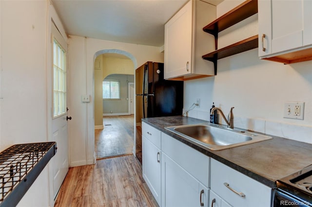 1707 W 39th Ave, Denver, CO 80211 - kitchen featuring open shelves, arched walkways, dark countertops, light wood finished floors, and white cabinets