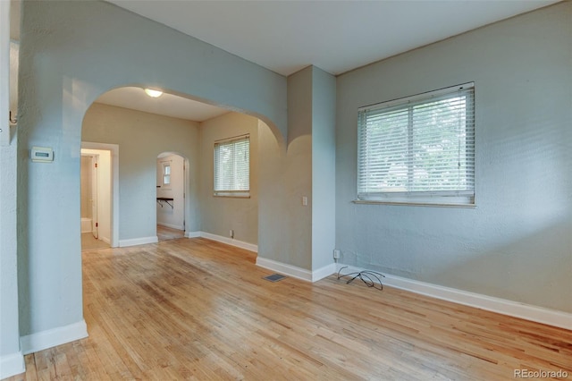 1707 W 39th Ave, Denver, CO 80211 - unfurnished room featuring arched walkways, healthy amount of natural light, and wood finished floors