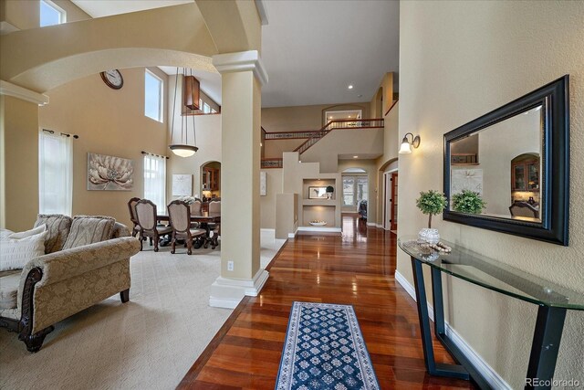 15258 W 75th Pl, Arvada, CO 80007 - foyer entrance with arched walkways, decorative columns, wood finished floors, a high ceiling, and baseboards